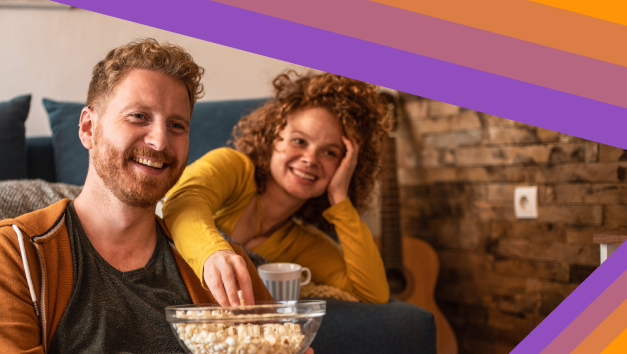 A woman having Pop corn on hand and enjoying TV show with coffee